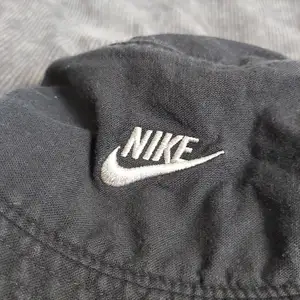 Snygg buckethat från Nike som tyvärr blivit för liten. Är ca 55 cm runtom. Är i en mörktblå/grå, lite urtvättad färg.