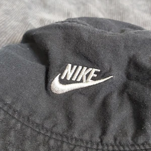 Nike buckethat - Snygg buckethat från Nike som tyvärr blivit för liten. Är ca 55 cm runtom. Är i en mörktblå/grå, lite urtvättad färg.