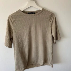 Beige T-shirt - Aldrig använd T-shirt från Boohoo. Den är för tajt i ärmarna för mig men annars snygga o lite längre ärmar😍 Är i ett ”halkigt” material. 