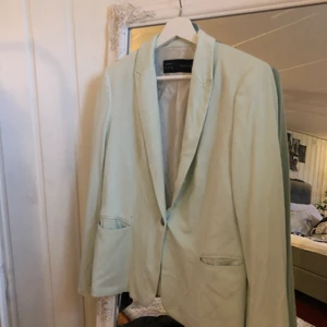 Kavaj från zara, storlek L - Figursydd kavaj från zara i en ljusgrön/mintgrön färg. Kavajen har axelvaddar och är enkelknäppt. Fint skick! Köparen står för frakten! (: