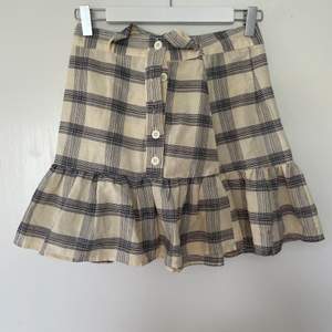 Mini kjol från Asos med knäppning för fram och band som knyts runt midjan. 