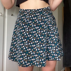 Blommig kjol - Blommig kjol med gröna, vita och gula/guldiga blommor. Skönt tunnt material och passar fint till varma sommardagar. Använd 1 gång💕