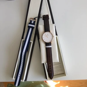Daniel Wellington klocka - Daniel Wellington klocka med brunt läderband. Oanvänt blått/vitt tygband ingår! Använd men i bra skick. Skicka ett meddelande för mer bilder! 