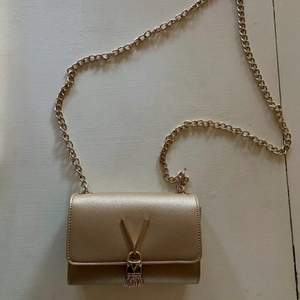 En guldig kuvertväska med kedjerem från Valentino. Helt perfekt skick, endast använd ett fåtal gånger. Originalpris 800 kr.