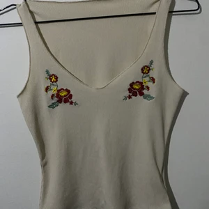 Blommigt linne - Fint cottage core aktigt linne med en djupare V ringning. Det har två broderade blom designs på båda sidor och är gjort av ett stretchigt material.