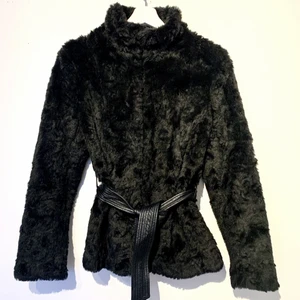 Svart pälsjacka med knytskärp/ stl. 38/ Fint skick  - Svart pälsjacka från H&M i fint skick. Stängs med integrerade knäppen samt ett läderskärp i midjan. Ej äkta päls. Storlek 38, använd 2 gånger. Jackan har en värmande krage. Kan postas spårbart mot betalning, (67 kr via Schenker eller 99 kr med Postnord).