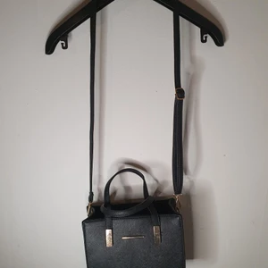 Svart axelremsväska - Säljer denna snygga axelremsväskan som är köpt från boohoo. Den är i gott skick med undantaget av skavanker a som visas på bilderna. Mitt pris 90kr.