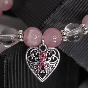 Armband - Handgjort armband med rosa bandet berlock. 50% av priset doneras till cancerforskning. Armbandet är gjort av högkvalite material med nickelfria metalldelar. 