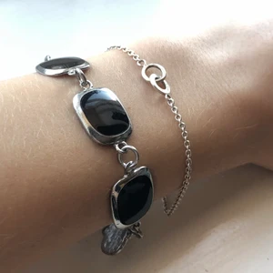 Palettarmaband med svarta detaljer - Silverpläterat palettarmband med svarta detaljer. Några små repor och slitningar på baksida palett, utöver det bra skick. Använd fåtal gånger