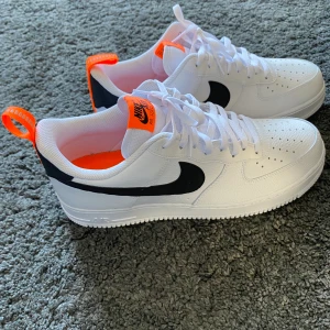 Nike skor nyskick - Vit nike air force 1 med svarta och orangea detaljer. Helt oanvända och passar perfekt nu till våren⚡️⚡️ Köparen står för frakten!