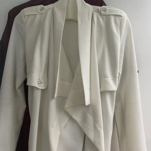 Trenchcoat strl S - Vit trenchcoat med axelvaddar. Hämtas i hallonbergen.