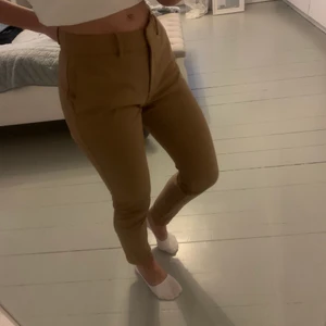 Kostymbyxor Gillian Tapered  - Helt nya, jättefina kostymbyxor med hög kvalitet. Säljer då de är lite för stora i midjan för just mig. Färgen är brun/beige och passformen ganska tight.       Ordinarie pris - 799kr