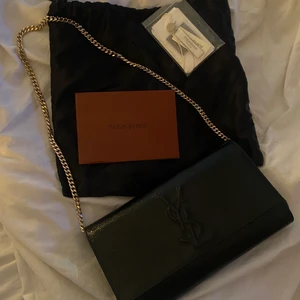 Yves Saint Laurent väska - Jätte fin YSL väska i modellen ”belle de jour patent leather clutch bag”. Det är en vintage model men som är väldigt klassisk och som nästan alltid trendat. Passar till allt och går att använda både som clutch bag och som en vanlig väska. Äktehetsintyg, dustbag och verifikation från Vestiare medkommer. Kostar 6500 ny.