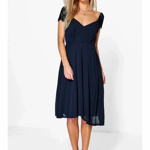 Klänning från boohoo - Elegant klänning från boohoo i färgen navy som aldrig blivit använd. Spets på ärmarna och dragkedja i ryggen. Storlek 42. Köpt för 225kr.