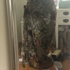 Lång Växtmönstrad Kjol - Väldigt fin men aldrig fått tillfälle att använda, därför säljer jag. Det är en omlott kjol, man knyter den runt midjan själv. Man kan ha den på många olika sätt, bilderna är bara ett av många sätt:) Köparen står för frakt🌞