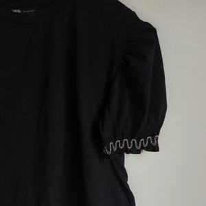 Svart T-Shirt med puffärmar - Säljer denna vackra t-shirt med puffärmar och en sorts ”volang” med tyll och pärlor. Passat perfekt till tex nyår eller till vardags. Säljer den då jag aldrig använder den. Inga skador finns. Det är storlek S och passar många olika. Köpare står för frakt!!🖤🖤🖤