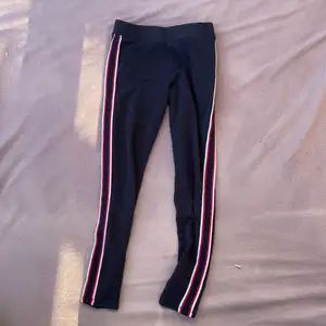 Ett par mörkblåa leggings från H&M med en röd vid och mörkblå rand på båda sidorna 