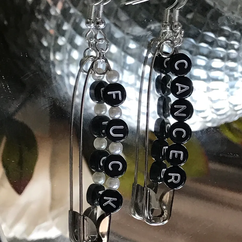Örhänge med svarta pärlor med texten ” fuck cancer” och vita runda pärlor 🟢finns i lager . Accessoarer.