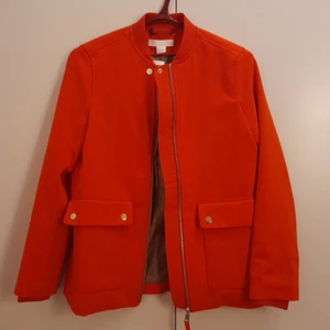 Orange/röd jacka strl 34 - Jacka från H&M. Längd 59 cm, strl 34. Ej använd.
