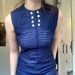 60 tals klänning  - fin mörkblå( och mycket genomskinlig) 60tals klänning. Vit knapp detalj på framsidan, och dragkedja där bak. Egentligen menad för barn. 