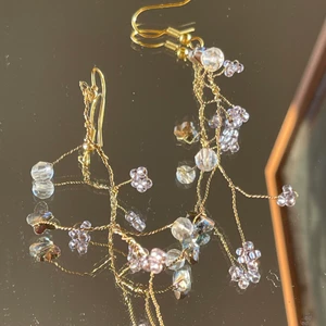 Handgjorda örhängen  - Ett par supersöta handgjorda örhängen med ljuslila glaspärlor och swarovski-kristaller!!!! 🦋🦋 Ca 7 cm, med tvinnad guldig ståltråd som bas, dock ”mjuka” i modellen och helt justerbara:)  ************************** Kolla gärna in min profil där jag har en massa mer smycken utlagda!! Frakt ingår i priset, perfekta för dig som vill sätta en personlig prägel på stilen eller att ge bort i present 🔮💕🧿
