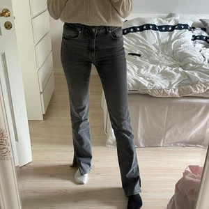 Bootcut jeans med slits från zara  - Ett par jättefina gråa jeans med slits från Zara. Säljer dem för att de är för stora på mig. Så de är endast använda några fåtal gånger. Skulle säga att de är ”mellan” höga i midjan men väldigt långa i benen! Är 173cm. Frakten är inte inkluderad. 