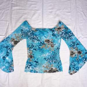 Blå vintage tröja med utsvängda ärmar som är blom- mönstrad. Den är stretchig så passar flera storlekar beroende önskad passform. Bra skick och endast använd en gång 