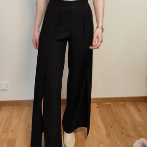 Svarta kostymbyxor med slits  - Högmidjade svarta kostymbyxor med slits! Sååå snygga när man går det blir ett härligt flow och en bit av benen tittar fram. Slitsen ä på båda sidor