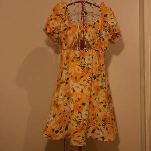 Jättefin orange/gul blommig klänning med puffärmar och cut-out med snörning under byst.