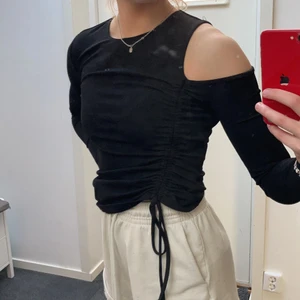 NAKD Svart festtop - Oanvänd svart Festtop från Nakd med detalj på sidan och hål för ena axeln. Materialet är inte see through alls och är bra kvalité. Säljes då den tyvärr aldrig användes 