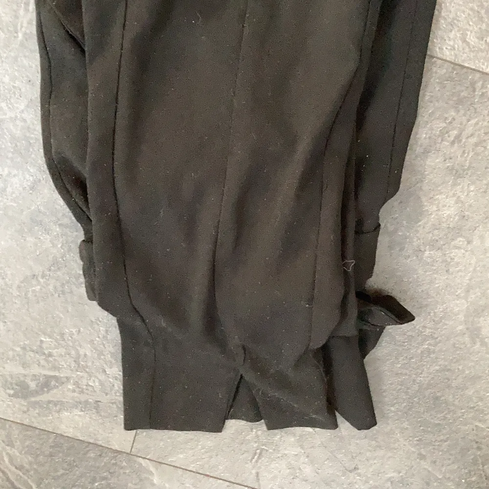 Svarta kostymbyxor med söm i mitten och en slits och igensydda fickor där bak, men som är för små. Jeans & Byxor.