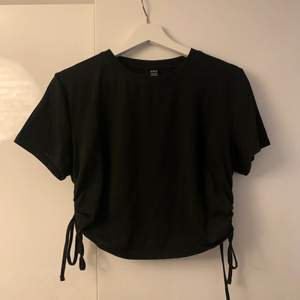 En oanvänd svart T-shirt. Storlek XL men mer L/M. Knytning i sidan