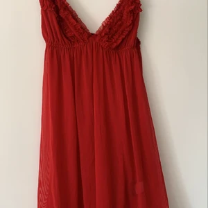 Röd mesh klänning med mini vollanger  - Plagget är en aning lingerie liknande men fungerar som en klänning på en utekväll. Dock är den väldigt genomskinlig nedanför bysten. Storleken är M men eftersom klänningen är stretchig skulle jag säga att den passar lika bra på någon med S. Köparen ansvarar för fraktkostnaden.