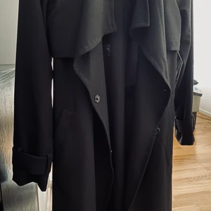 Svart trenchcoat - Säljer nu denna supersnygga trenchcoaten då den är för liten för mig! Använd men i bra skick! Perfekt nu till hösten! Priset är inklusive frakt<3