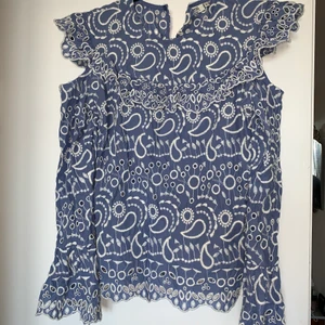Blå blus med vita detaljer - Superfin mellanblå blus med vita detaljer och cutouts.