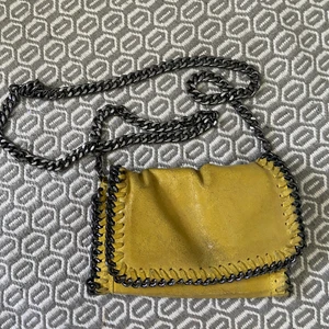 Gul liten väska  - Säljer min fina lilla gula väska som är köpt i Spanien! Den är i äkta läder och har en lång kedja som man kan göra kortare beroende på hur man vill ha den! Den har en dragkedja till de stora facket inuti väskan.