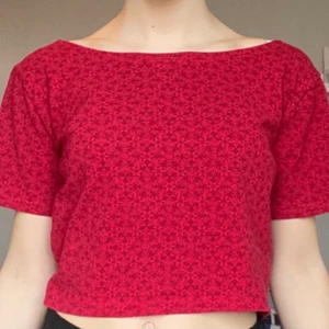 Röd tisha från beyond retro - Säljer denna röda, småblommiga t-shirt/topp med djup rygg jag köpte från beyond retro i somras. Oanvänd!!! Spårbar frakt kostar extra.