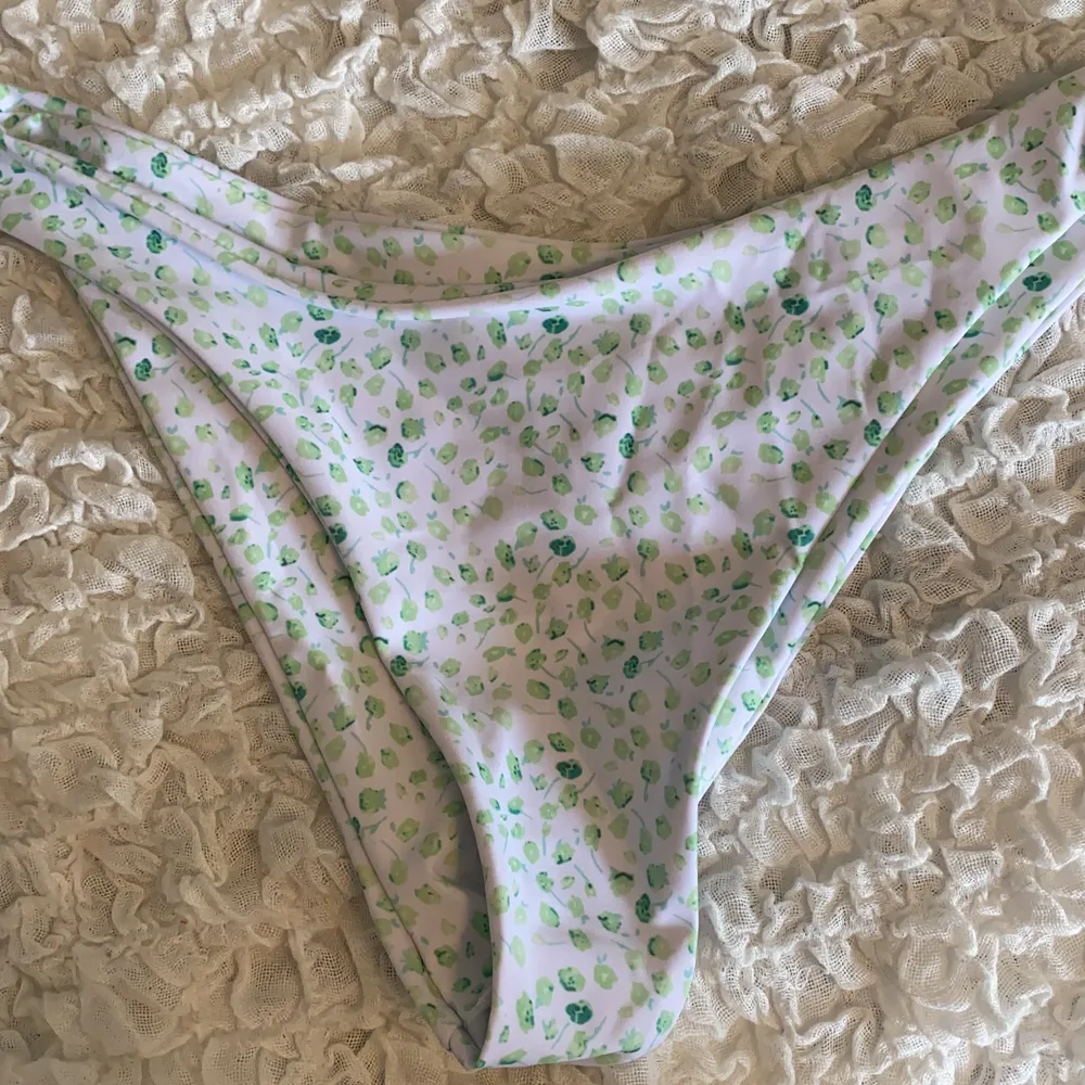 En vit bikini med gröna blommor som jag nyss köpt men den passade inte. Den är endast provad och har kvar plombering i bikinitrosan! 💚. Toppar.