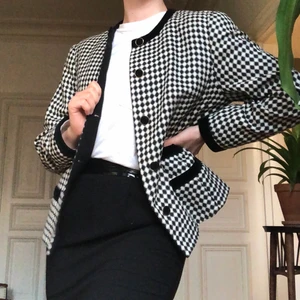 Svartvit-rutig jacka - Stilig, axelvadderad, vintage-jacka/kavaj i svartvitt, rutigt mönster. De helsvarta detaljerna på jackan är sammet, även knapparna. 