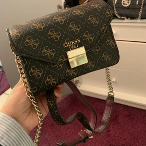 Väska - Guess väska! Rätt så liten och kommer med ett längt axelband🥰 lite rost runt märket men inget man märker jättemycket 