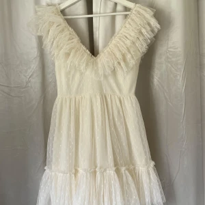 Studentklänning  - Krämvit supersöt studentklänning med volanger, dolt blixtlås bak. Använd en gång förra året på min student, är i mycket bra skick och passar på storlek S! Jag är 160cm som referens.