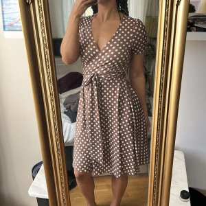 Brun prickig klänning - Sommarens måste ha  Superskön och mjuk omlottklänning i brunt med vita prickar på 🤎