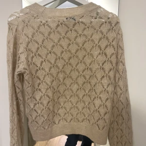Stickad tröja - En beige stickad tröja från Nelly. Den är ny och använd ändast en gång. 