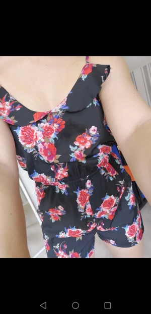 Somrig byxdress - Somrig, blommig byxdress. Använd ett fåtal gånger. Står storlek EU 38 och UK 10, men jag skulle säga att det är en small. OBS!! Ena bandet har platsbiten gått sönder, så man behöver sy ett stopp själv på den längden man önskar. 