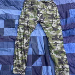 Vintage camo - Camobyor i bra Cond, resårband som man kan knyta vid midjan, 4 fickor totalt! Midjemått rakt över 42 cm, totala längd 104 cm, benöppning 16 cm. Dm vid frågor:)