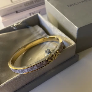 MICHAEL KORS armband - Säljer detta helt oanvända äkta Michael kors armbandet i guld. Aldrig använt då de är lite för stort för mig så väljer därför att sälja det. Köpt för 1200kr men pris kan diskuteras🩷