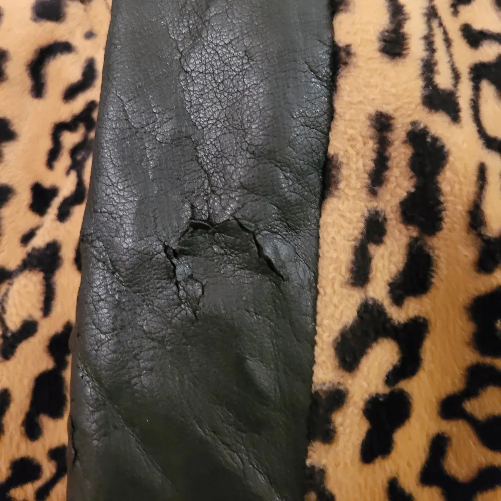 Leopardmönstrad kappa/jacka med två fickor. Detaljerna på ryggen går att vända på så det antingen är fake skinn utåt eller samma leopardtyg utåt.   Det är bara 2 knappar kvar och fake skinnet har börjat spricka lite på ena armbågen (bild 3). . Jackor.