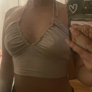 glittrig topp - en fin beige topp från gina tricot, använd en gång. kan knytas därbak