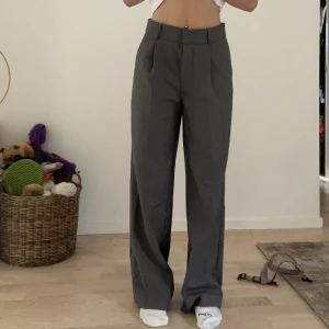Lågmidijade Kostymbyxor - Grå kostymbyxor från Gina tricot! Säljer pågrund av att de är alldeles för stora för mig! Står att det är XS på lappen men skulle säga att det är S/M kanske, sitter hyfsat bra i midjan men alldeles för stor runt låren! Aldrig använd!!!