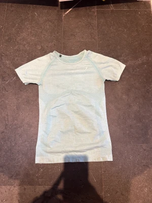Gymshark T-shirt 🩵 - Så fin. Storlek s. Små defekter. Fläckarna syns på bilderna. Utöver det, perfekt skick. Denna säljs inte längre på hemsidan.  Försten till kvarn. Klicka gärna på köp nu ❤️